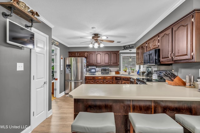 kitchen featuring stainless steel fridge, range with electric cooktop, light countertops, crown molding, and a peninsula
