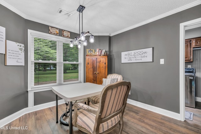 dining room with wood finished floors, ornamental molding, baseboards, a chandelier, and washer / dryer