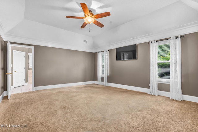 spare room featuring light carpet, a ceiling fan, baseboards, a raised ceiling, and ornamental molding