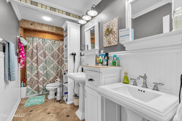bathroom with a shower with curtain, a sink, toilet, stone finish floors, and baseboards