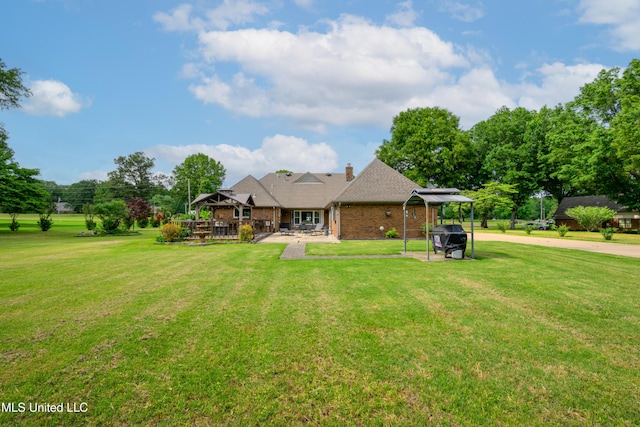 back of property with a gazebo, a yard, brick siding, and a chimney