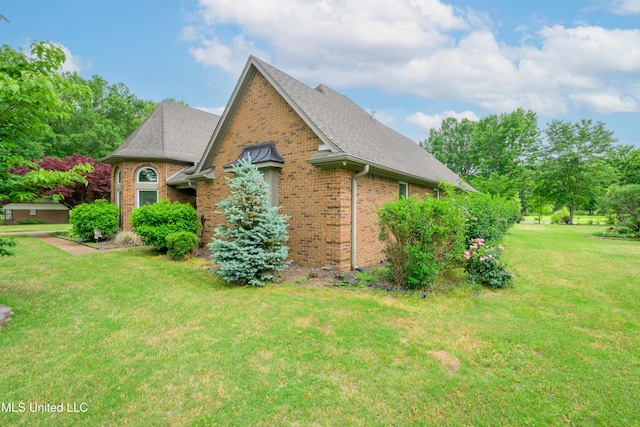 view of property exterior featuring brick siding, a yard, and a shingled roof
