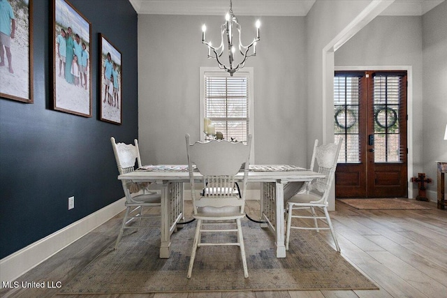 dining room featuring french doors, an inviting chandelier, ornamental molding, wood finished floors, and baseboards