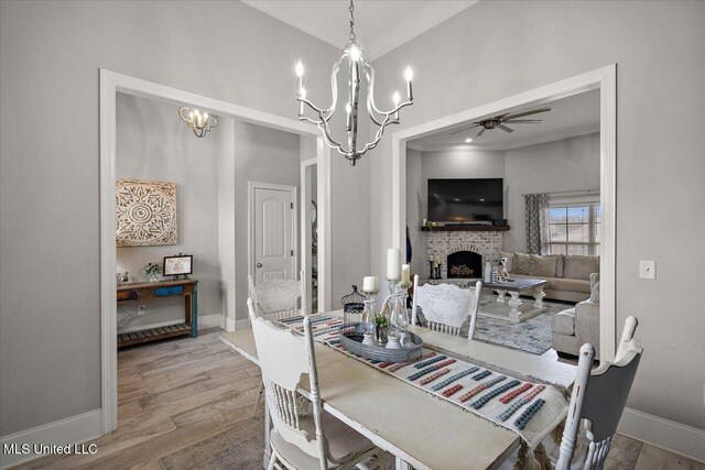 dining room featuring a brick fireplace, baseboards, and wood finished floors