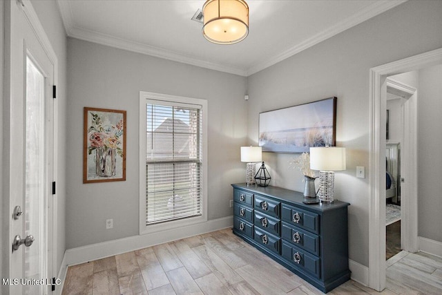 interior space featuring light wood-style floors, crown molding, and baseboards