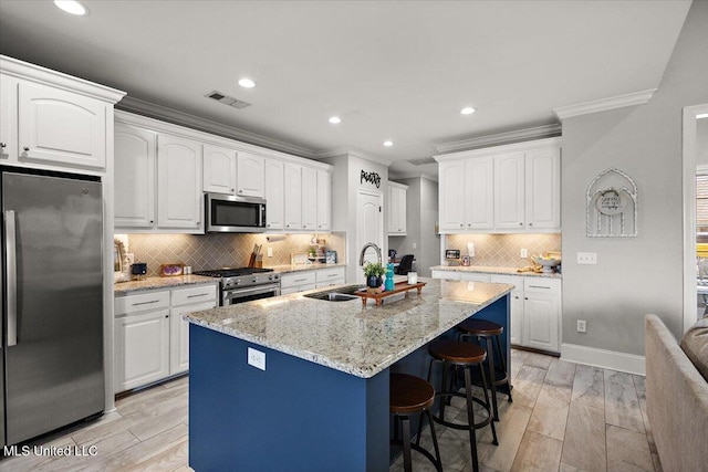 kitchen with appliances with stainless steel finishes, a sink, white cabinets, and crown molding