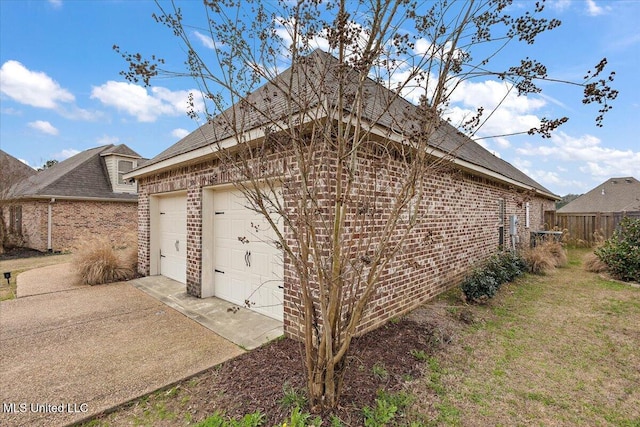 view of side of property with a garage, fence, and brick siding