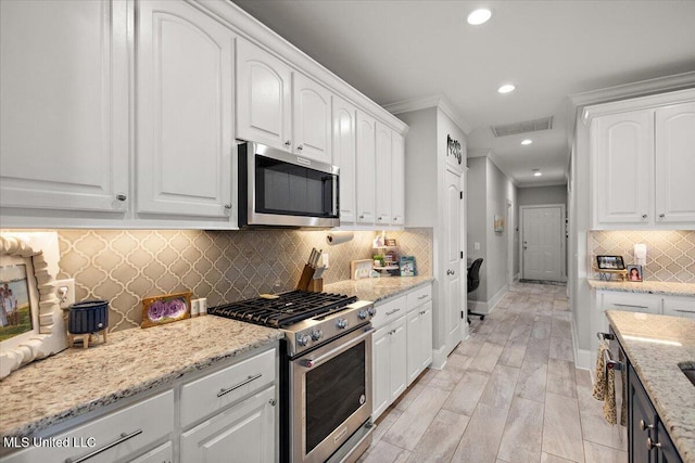 kitchen with stainless steel appliances, decorative backsplash, visible vents, and white cabinets