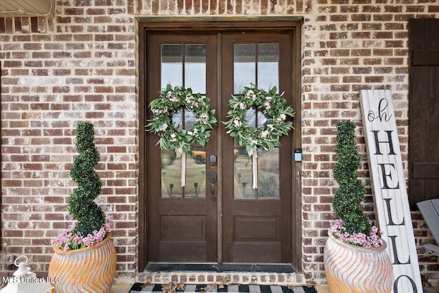 property entrance featuring french doors and brick siding