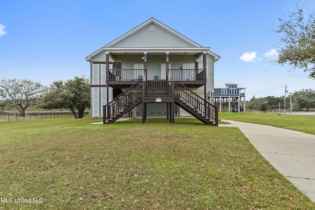 coastal inspired home featuring fence, stairway, a porch, and a front yard