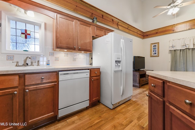 kitchen with white appliances, a sink, light countertops, light wood-type flooring, and brown cabinets