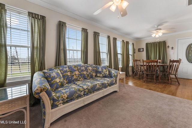 living area with ornamental molding, wood finished floors, and a ceiling fan