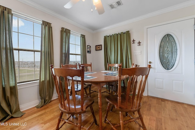 dining space with light wood finished floors, ceiling fan, ornamental molding, and visible vents