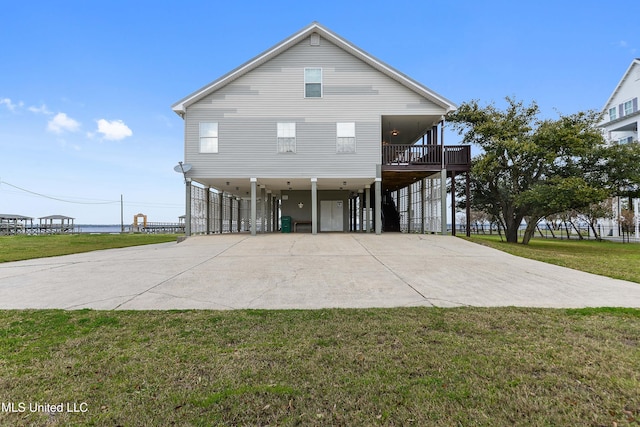 rear view of property featuring a yard, a carport, and concrete driveway