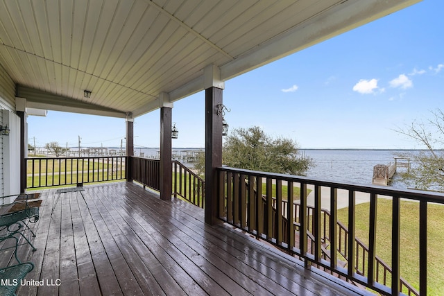 wooden deck with a water view and a lawn