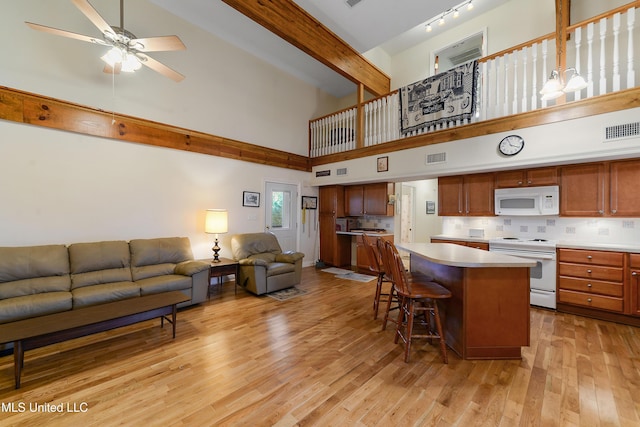 kitchen featuring light countertops, visible vents, open floor plan, a kitchen island, and white appliances