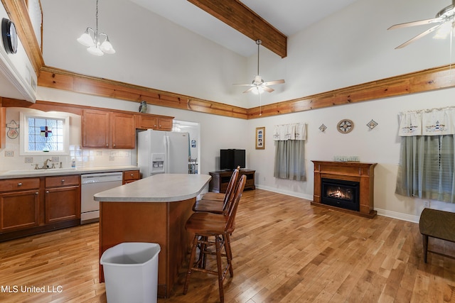 kitchen with brown cabinets, white refrigerator with ice dispenser, light countertops, and dishwashing machine