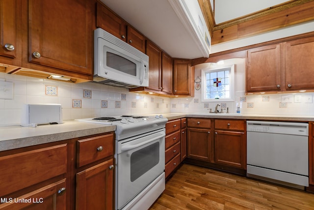 kitchen featuring dark wood-style floors, light countertops, decorative backsplash, a sink, and white appliances