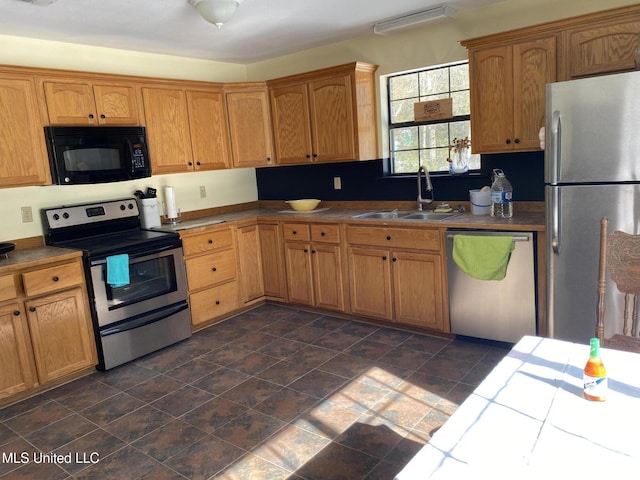 kitchen with appliances with stainless steel finishes, tile counters, and sink