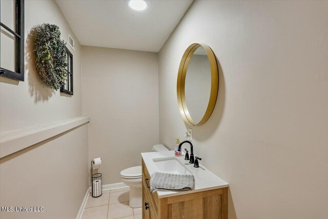 half bath with toilet, vanity, tile patterned flooring, baseboards, and visible vents