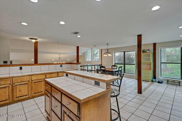 kitchen featuring tile counters, visible vents, light tile patterned floors, and an inviting chandelier