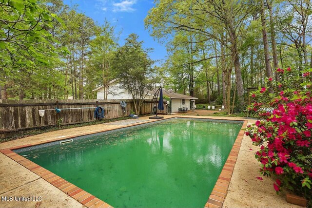 view of swimming pool featuring an outdoor structure, a fenced backyard, and a fenced in pool