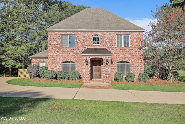 view of front of property featuring brick siding, a front lawn, and a shingled roof