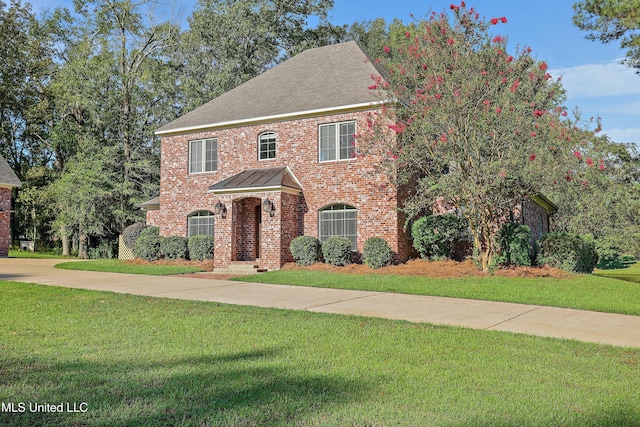 view of front of home with roof with shingles, brick siding, a front lawn, and concrete driveway