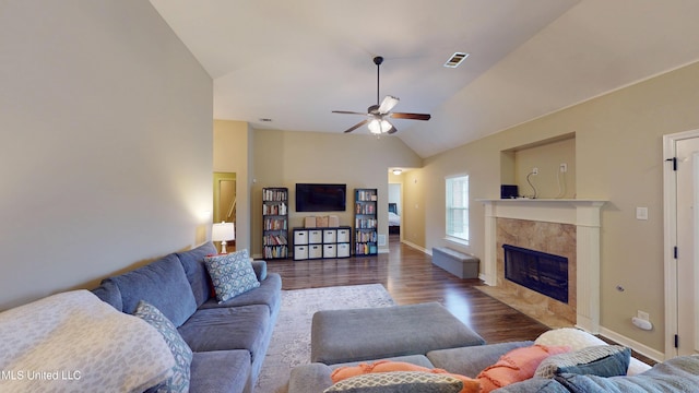 living room featuring dark wood-type flooring, a tile fireplace, ceiling fan, and vaulted ceiling