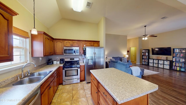 kitchen featuring pendant lighting, sink, appliances with stainless steel finishes, high vaulted ceiling, and a center island