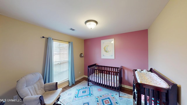 bedroom featuring light hardwood / wood-style flooring and a crib