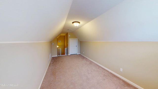 additional living space featuring vaulted ceiling and light carpet