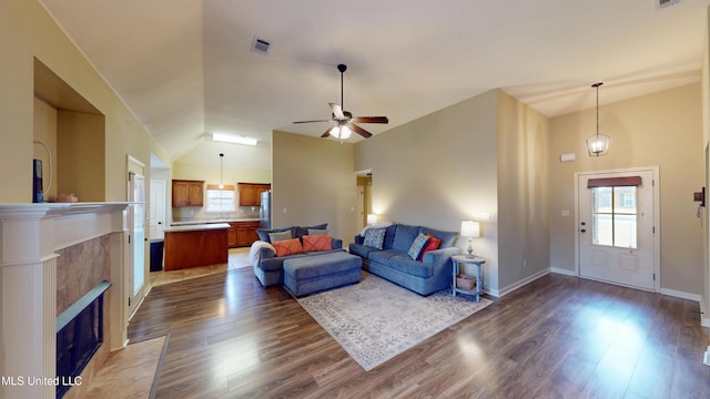 living room with dark hardwood / wood-style floors, a tiled fireplace, and high vaulted ceiling