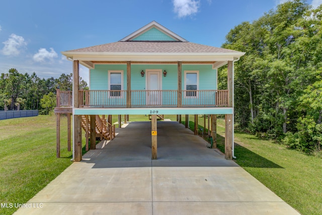 beach home with a front lawn, covered porch, and a carport