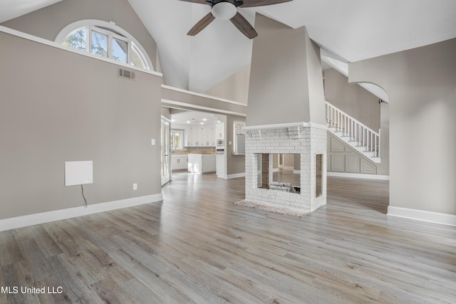 unfurnished living room featuring a fireplace, light wood-type flooring, a wealth of natural light, and ceiling fan