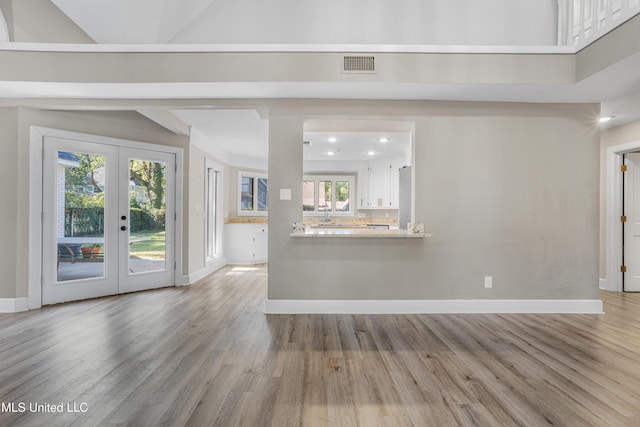 unfurnished living room with french doors and light hardwood / wood-style floors