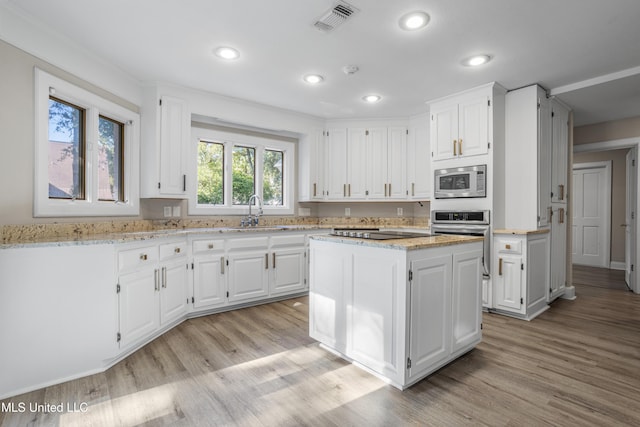 kitchen featuring white cabinetry, a center island, sink, stainless steel appliances, and light hardwood / wood-style flooring