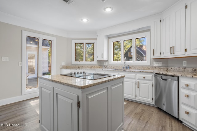 kitchen with stainless steel dishwasher, a kitchen island, black electric cooktop, light hardwood / wood-style floors, and white cabinetry