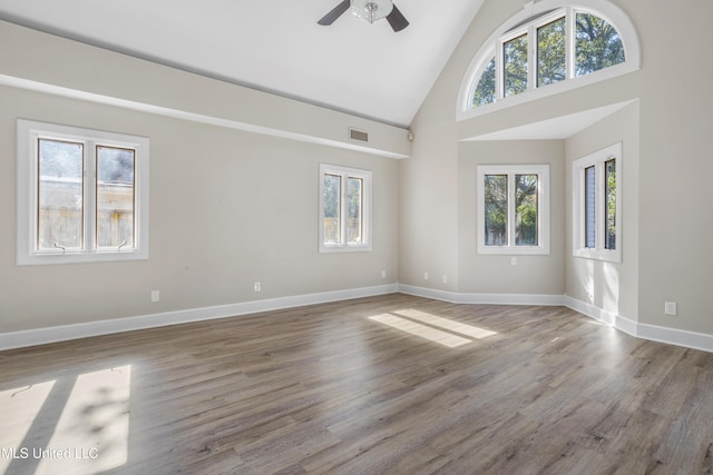 unfurnished living room featuring ceiling fan, hardwood / wood-style floors, high vaulted ceiling, and plenty of natural light