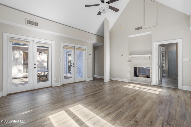 unfurnished living room featuring french doors, ceiling fan, high vaulted ceiling, a fireplace, and hardwood / wood-style floors