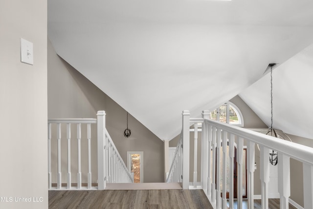 staircase with wood-type flooring and vaulted ceiling