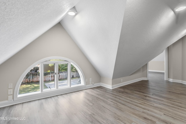 unfurnished living room with hardwood / wood-style floors, lofted ceiling, and a textured ceiling