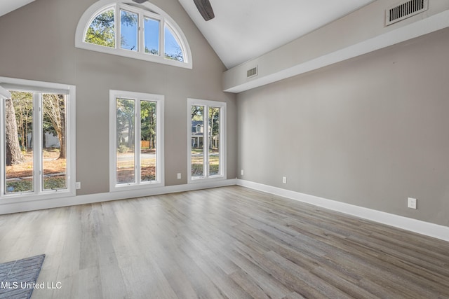 unfurnished living room with ceiling fan, high vaulted ceiling, and wood-type flooring