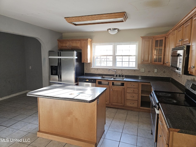 kitchen featuring decorative backsplash, sink, stainless steel appliances, and a center island