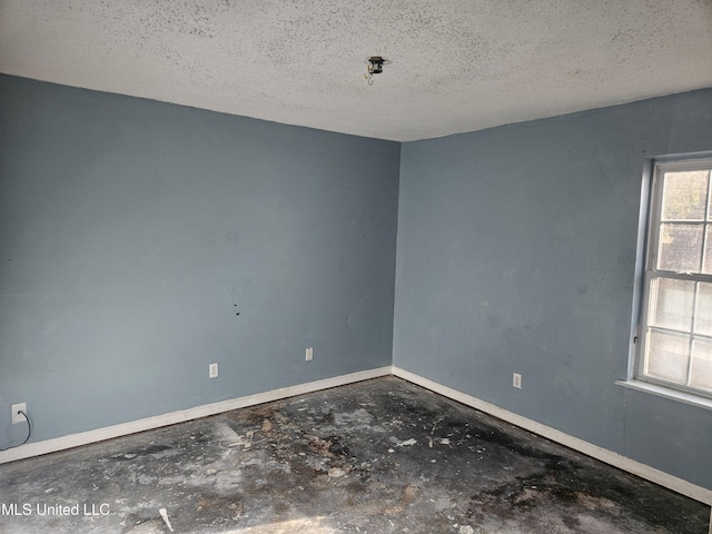 empty room with a textured ceiling and concrete flooring