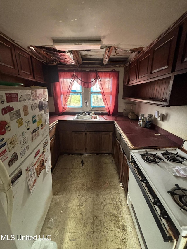 kitchen featuring dark countertops, white appliances, light floors, and a sink