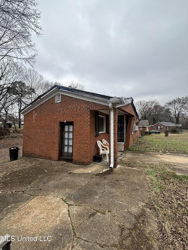 view of side of home with brick siding and a patio