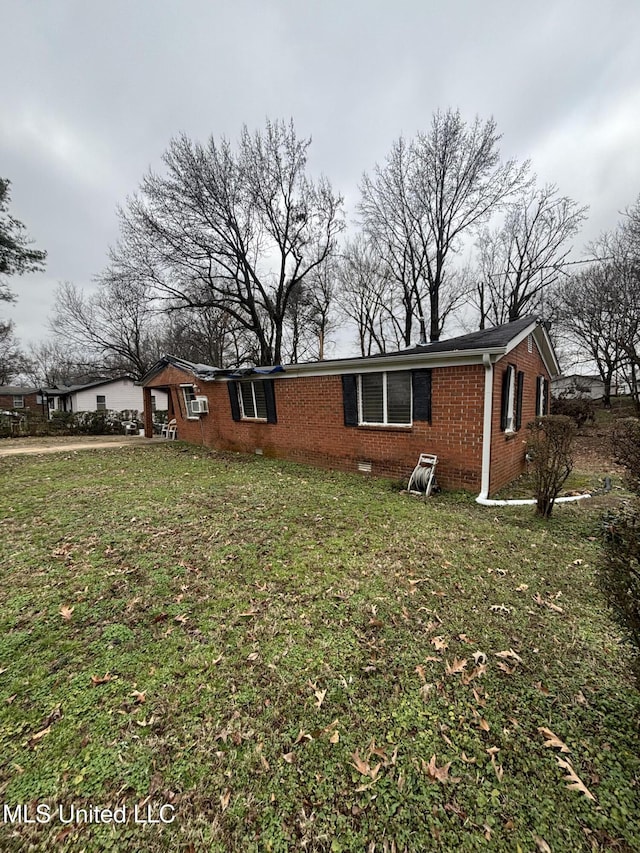 view of side of home with crawl space, brick siding, a yard, and an attached garage