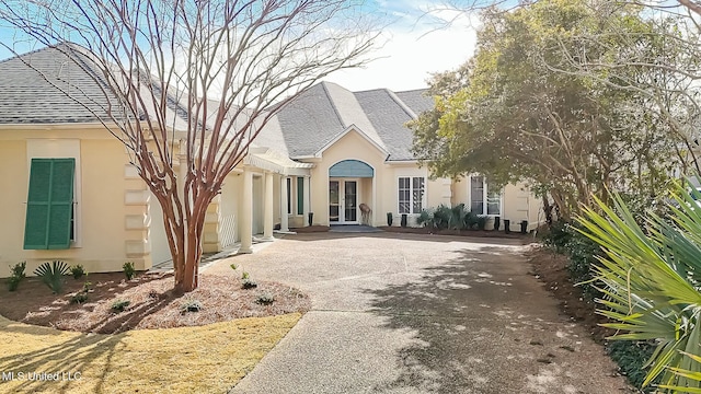 view of front of property with french doors, a shingled roof, driveway, and stucco siding