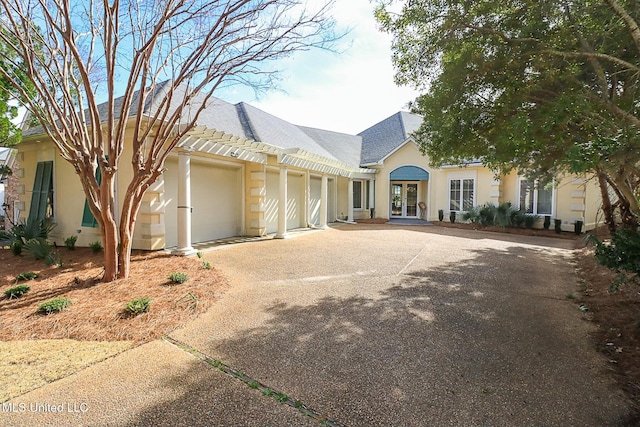 view of front of house featuring stucco siding, french doors, concrete driveway, and an attached garage